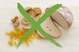 Različna živila, ki vsebujejo gluten – kruh, testenine, piškoti in žita – z zelenim križem čez, kar simbolizira izogibanje glutenu.